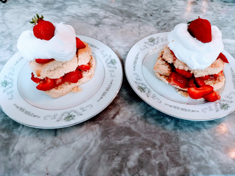 A pair of strawberry shortcakes with freshly whipped cream.