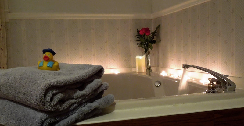 The Jacuzzi for two is surrounded by candles to light with pillows, aromatherapy and a rubber ducky.