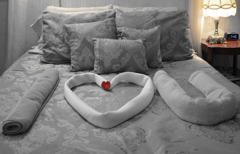 Romantic Retreat Suite and a comfortable bed and oasis awaits guests with I heart you spelled out on the bed.