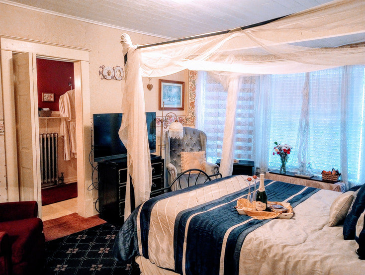 Romantic Victorian Room offers a queen canopy bed, comfortable seating for two, along with a lovely bay window.